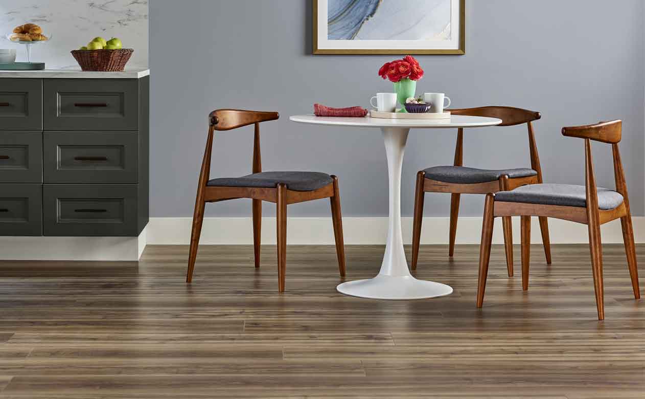 Wood look vinyl flooring in kitchen with white table and wooden chairs and gray blue walls